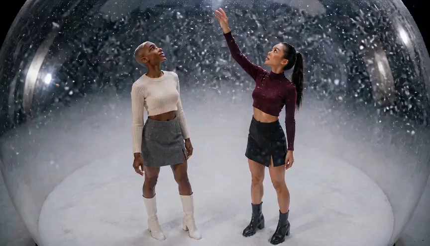 巨大なスノードームの中で、ふたりの女性のまわりを雪が回る